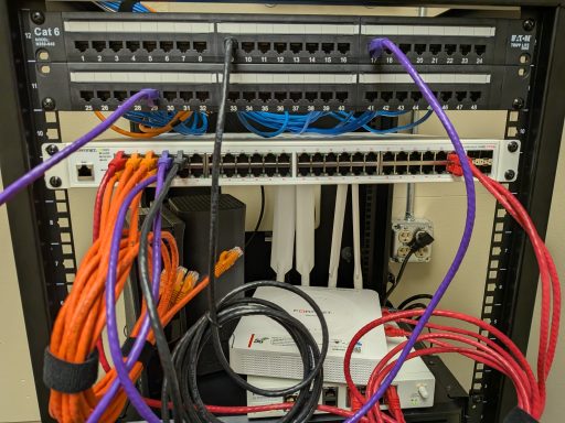 A rack of network equipment with various color-coded cables connected.